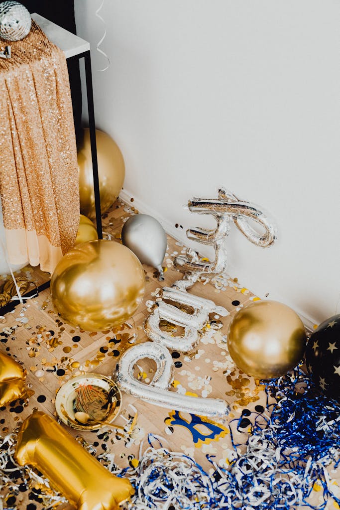 Festive gold and silver balloons with confetti creating a celebratory New Year's Eve atmosphere.